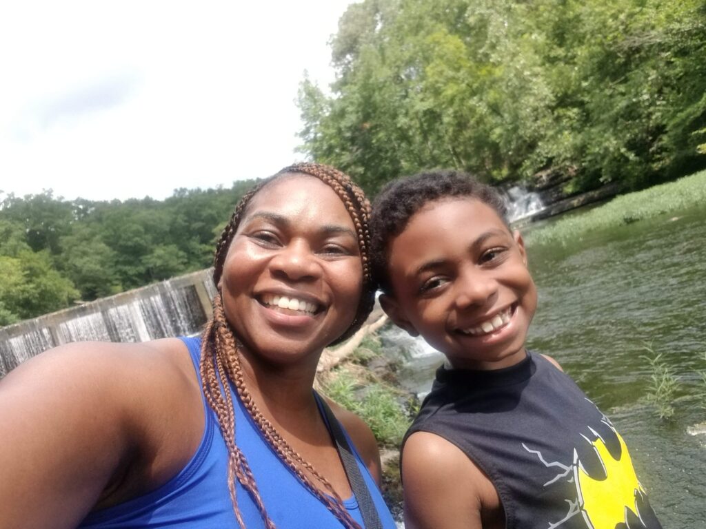 Dr. Lametra Scott and her son Rickey, who received sickle cell gene therapy, smiling together outdoors